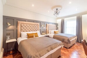 A hotel room with two beds, a modern chandelier, and a large window with curtains. - King Street Aparthotel (Stirling)