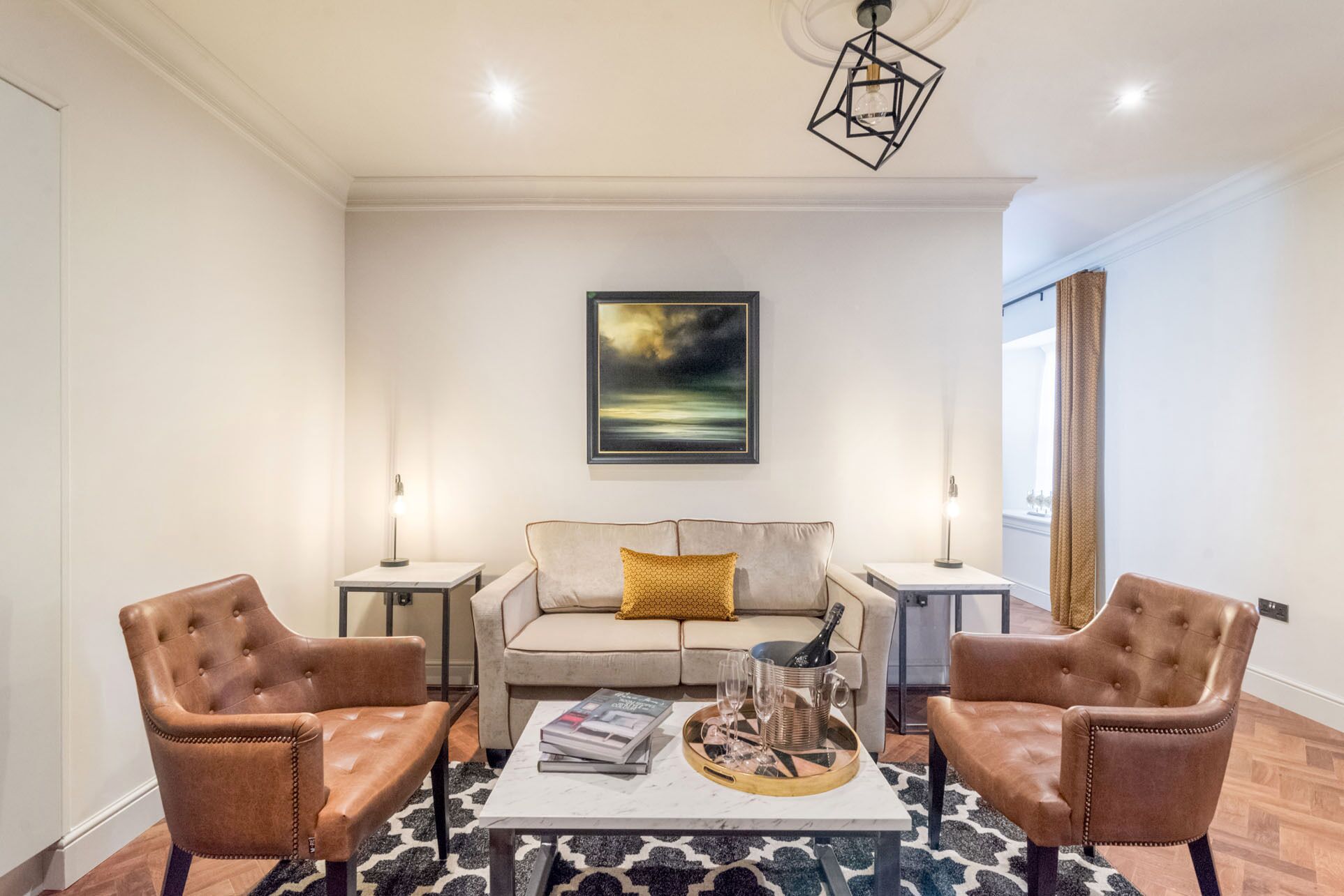 A modern living room with a sofa, two armchairs, a coffee table, and a painting on the wall.