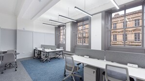 A modern office space with cubicles, desks, chairs, and large windows offering views of buildings. - King Street Aparthotel (Stirling)