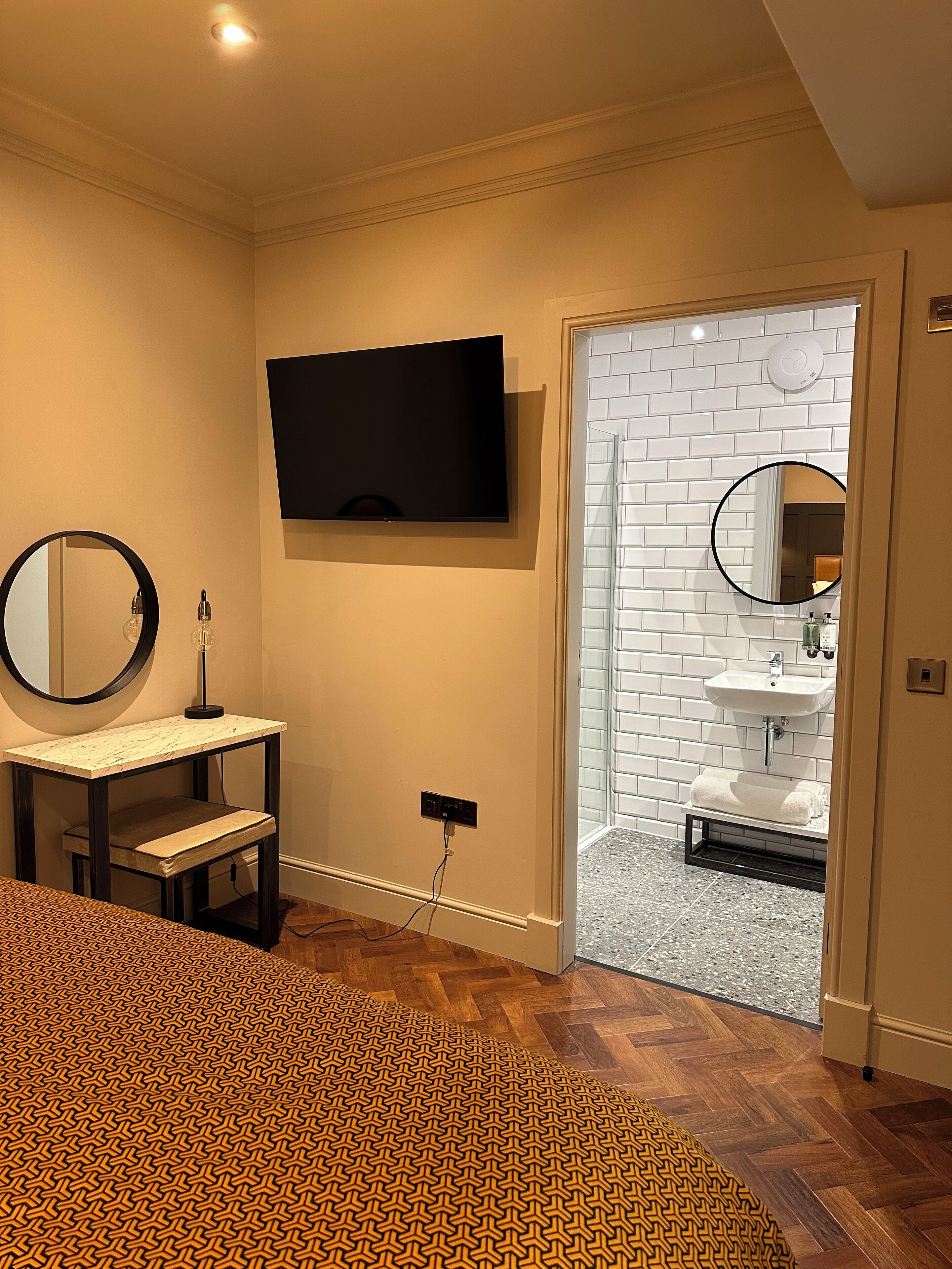 Une salle de bain moderne avec un téléviseur fixé au mur, un lavabo avec un miroir et un carrelage décoratif.