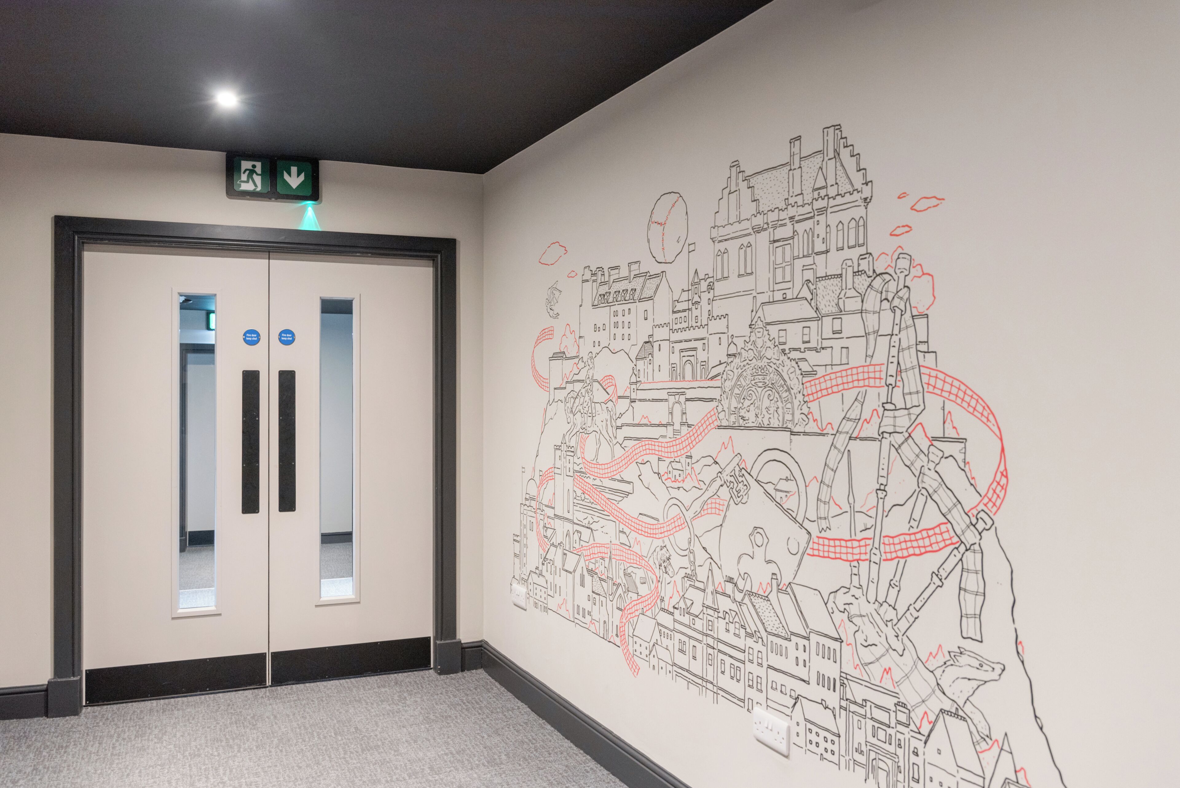 A hallway with a double door, a wall mural, and a ceiling light.