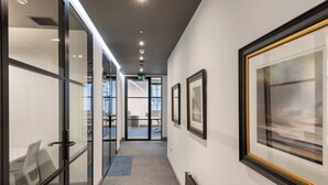 A hallway with glass walls, framed artwork, and a carpeted floor. - King Street Aparthotel (Stirling)