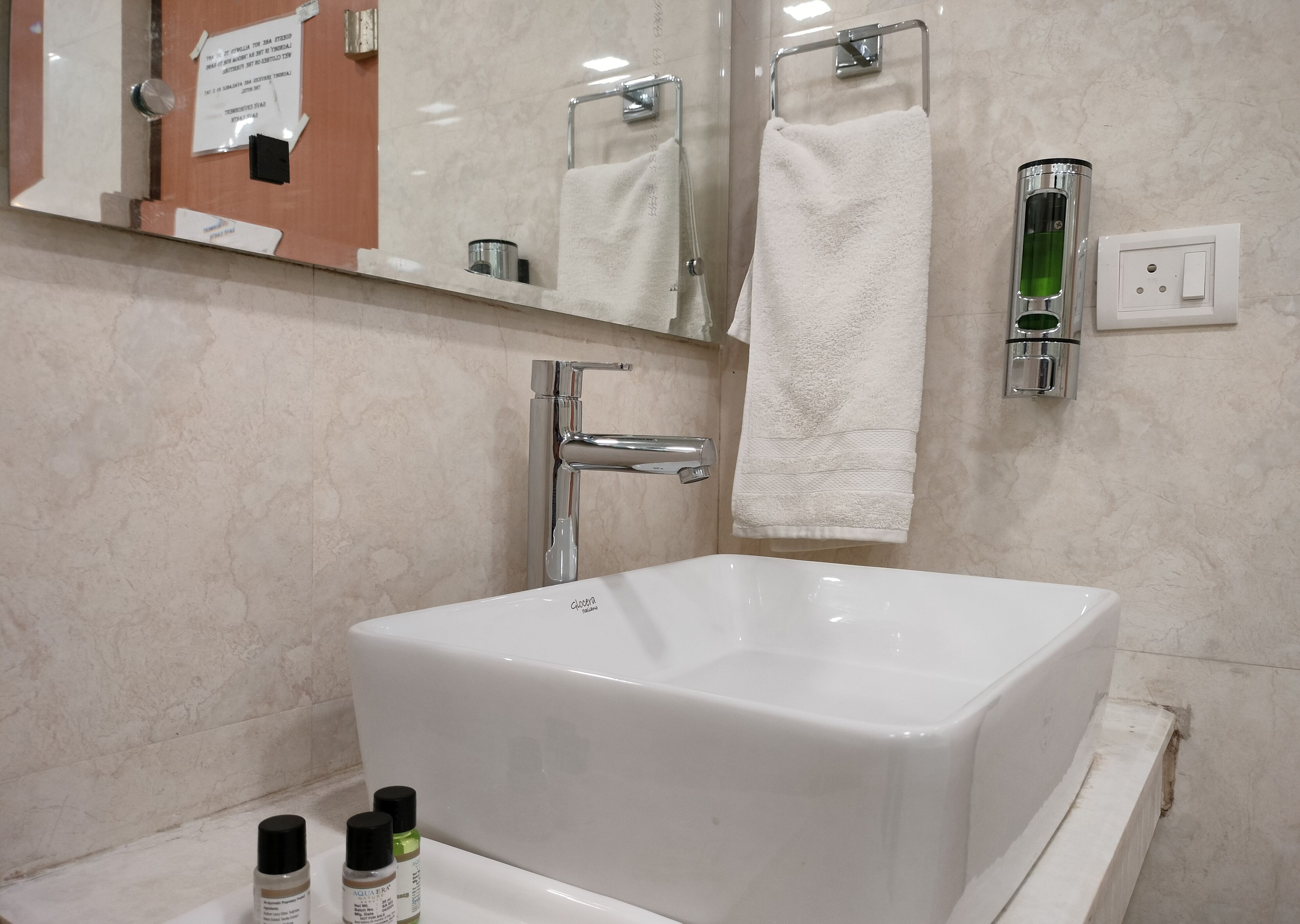 A modern bathroom with a large white bathtub, a chrome faucet, and a mirror above the sink. There are two bottles of toiletries on the sink counter.