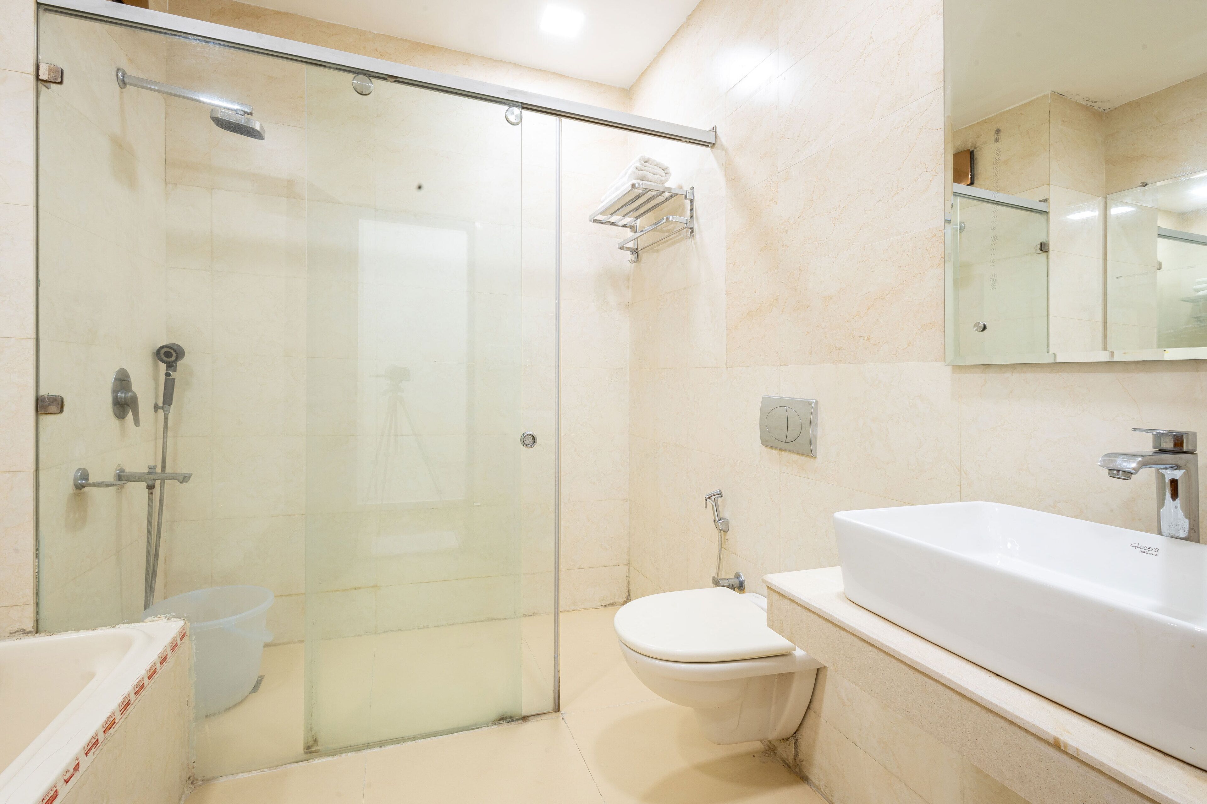 A modern bathroom with a glass-enclosed shower, a toilet, and a large white sink.