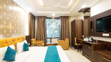 A hotel room with a large bed, a TV, a desk, and a view of the outdoors.