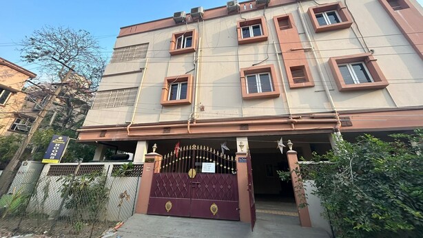 A multi-story building with a gated entrance, multiple windows, and a sign indicating "Rooms". - Orchid Residency Medavakkam (Chennai)