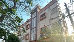 A multi-story residential building with a gated entrance, a parked car, and a visible signboard. - Orchid Residency Medavakkam (Chennai)