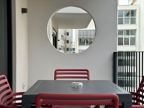 A balcony with a table and chairs, a round mirror, and a view of buildings in the background. - M & M 5 in the city (XP92+FQ Athens, Greece)