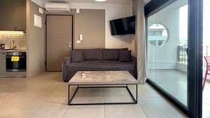 A modern living room with a sofa, a coffee table, a TV, and a balcony with a glass door. - M & M 5 in the city (XP92+FQ Athens, Greece)