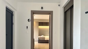 A hotel corridor with a bed, a door, and a security camera. - M & M 5 in the city (XP92+FQ Athens, Greece)