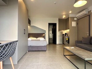 A modern hotel room with a bed, a desk, a chair, a sofa, and a kitchenette. - M & M 5 in the city (XP92+FQ Athens, Greece)