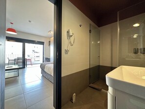 A modern bathroom with a glass shower enclosure, a white sink, and a telephone mounted on the wall. - M & M 5 in the city (XP92+FQ Athens, Greece)