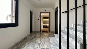 A hallway with marble flooring leading to a bedroom with a bed and a nightstand. - M & M 5 in the city (XP92+FQ Athens, Greece)