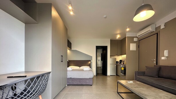 A modern hotel room with a bed, a desk, a sofa, and a kitchen area. - M & M 5 in the city (XP92+FQ Athens, Greece)