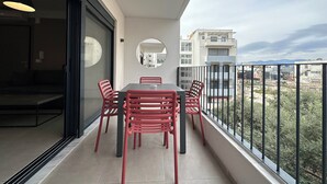 A balcony with a dining table and chairs, a round mirror, and a view of buildings and mountains. - M & M 5 in the city (XP92+FQ Athens, Greece)