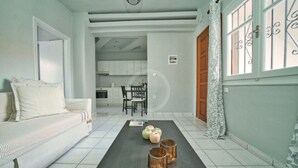 Een moderne woonkamer met een bank, een eettafel met stoelen, en een keuken op de achtergrond.