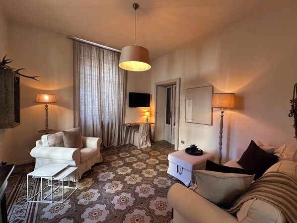 A cozy living room with a patterned carpet, a sofa, a chair, a small table, and a lamp.