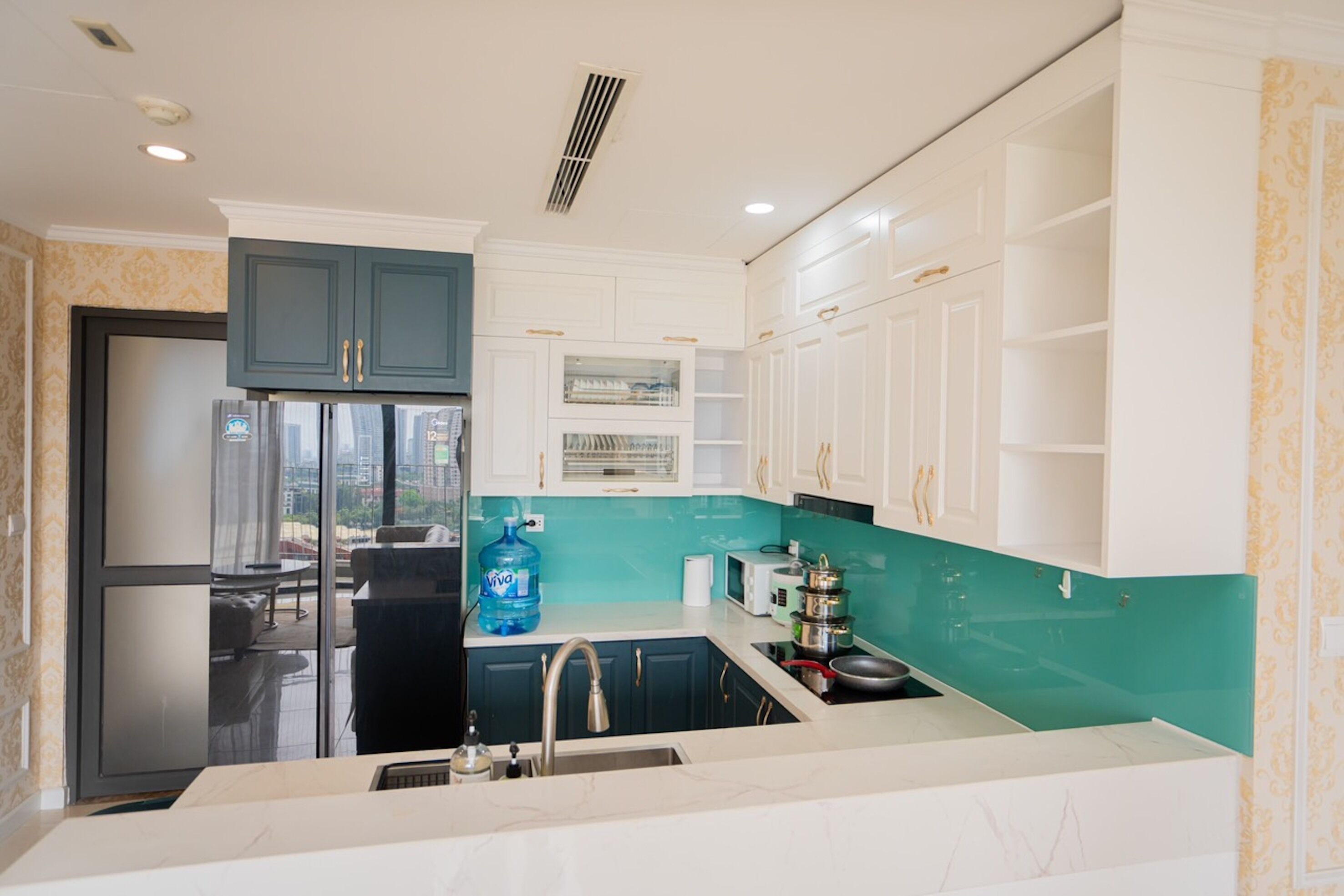A modern kitchen with teal backsplash, white cabinets, and stainless steel appliances.