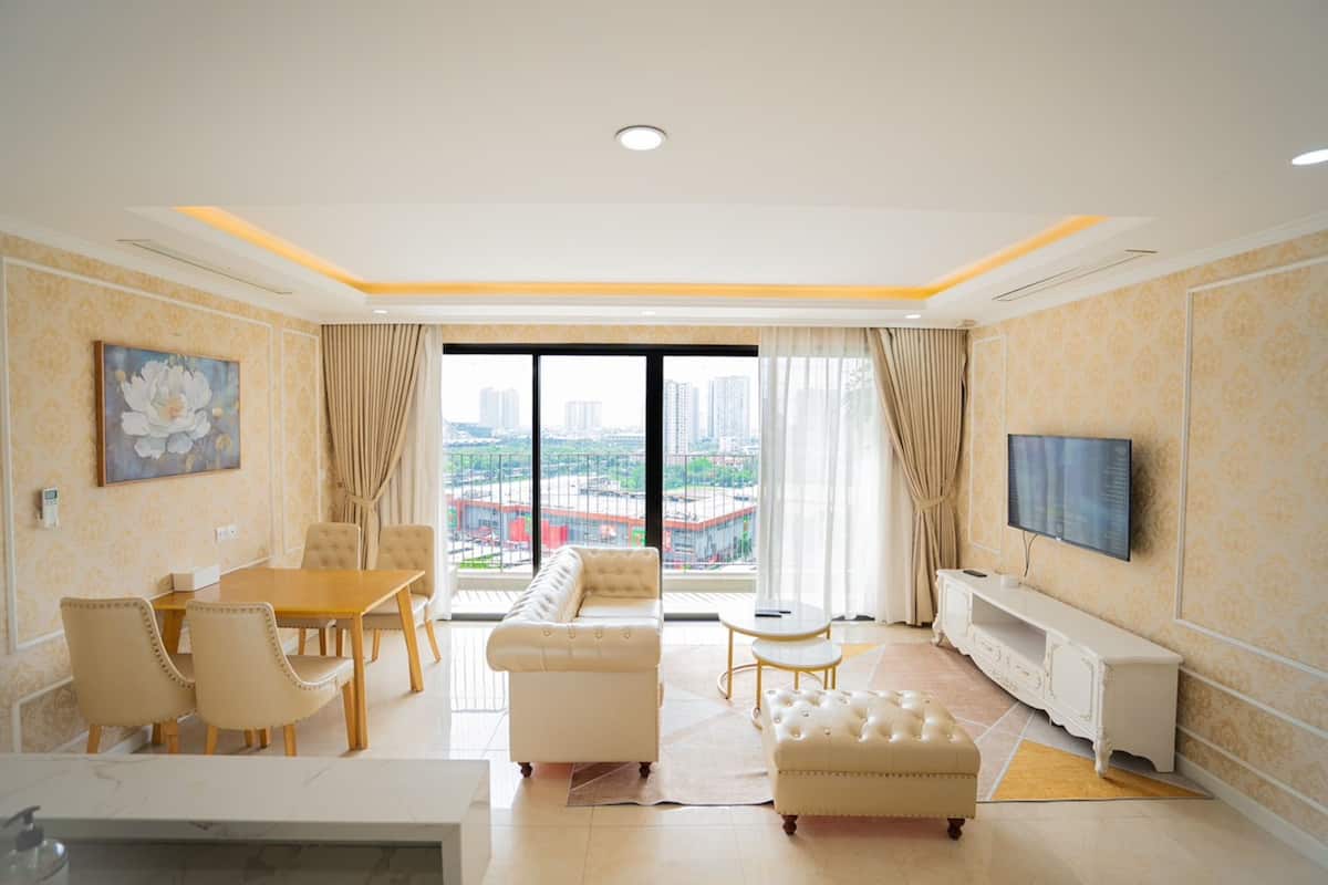 A modern living room with a dining area, a sofa, a TV, and a city view through large windows.
