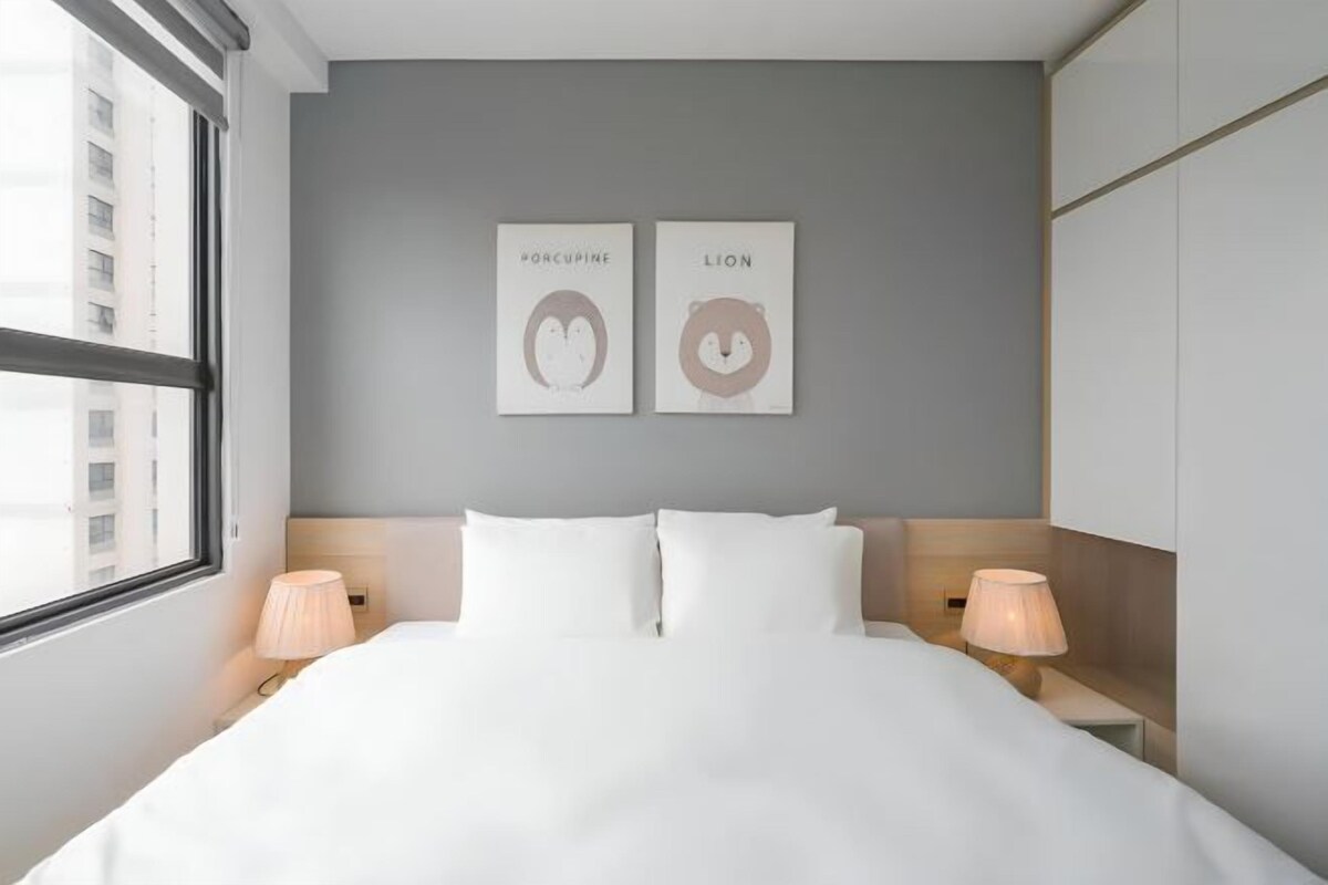 A hotel room with a large bed, two bedside lamps, and two framed animal illustrations on the wall.