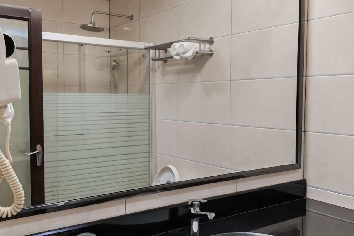 Ein Badezimmer mit Spiegel, Telefon, Handtuchhalter und Duschbereich.