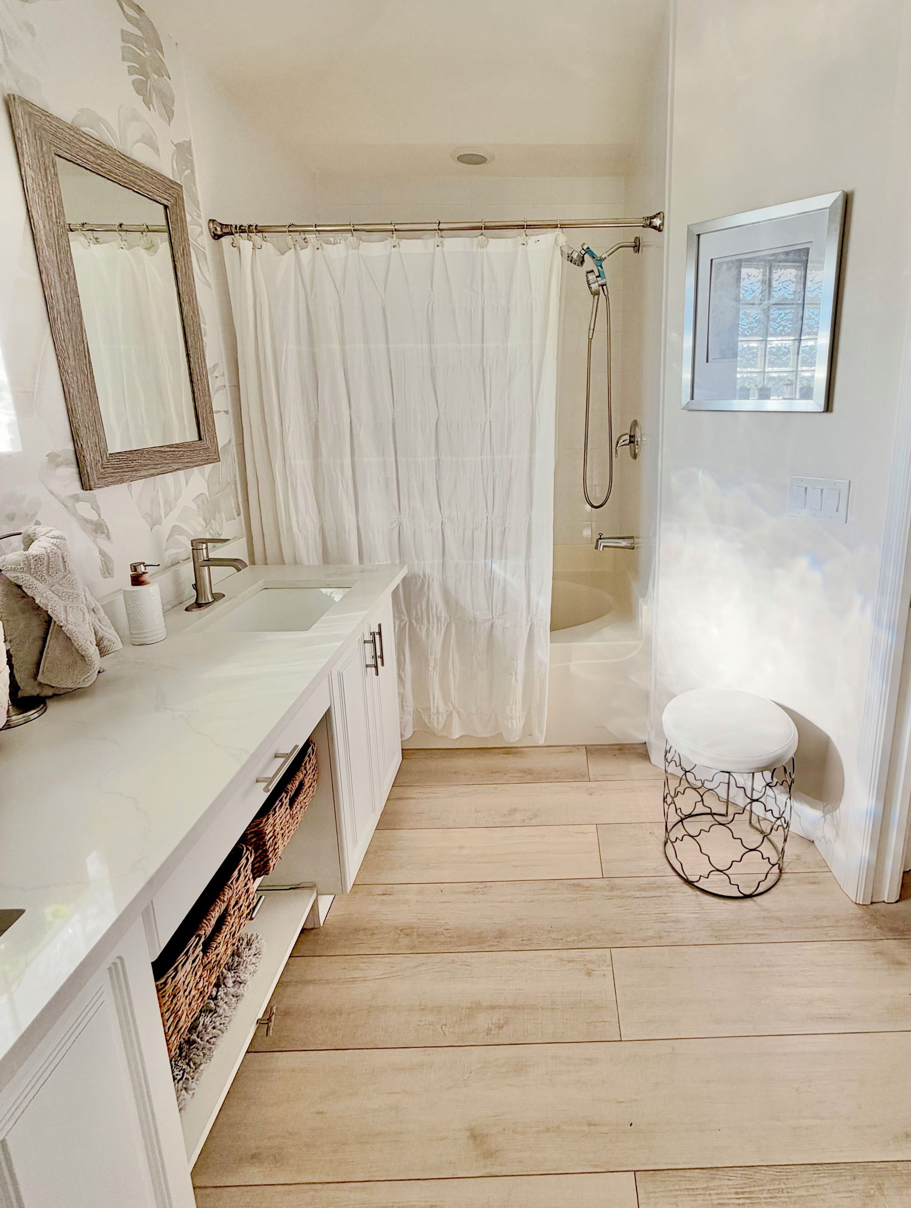 A bathroom with a shower, a sink, a mirror, and a toilet.