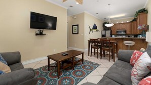 Una sala de estar con televisión, sofá, mesa de centro y alfombra estampada.