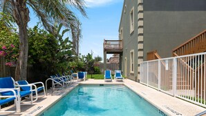 Una piscina con sillas azules y una cerca blanca.