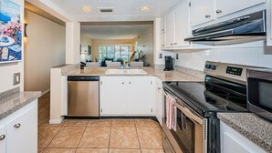 Una cocina moderna con gabinetes blancos, encimera de granito, electrodomésticos de acero inoxidable y una isla central.