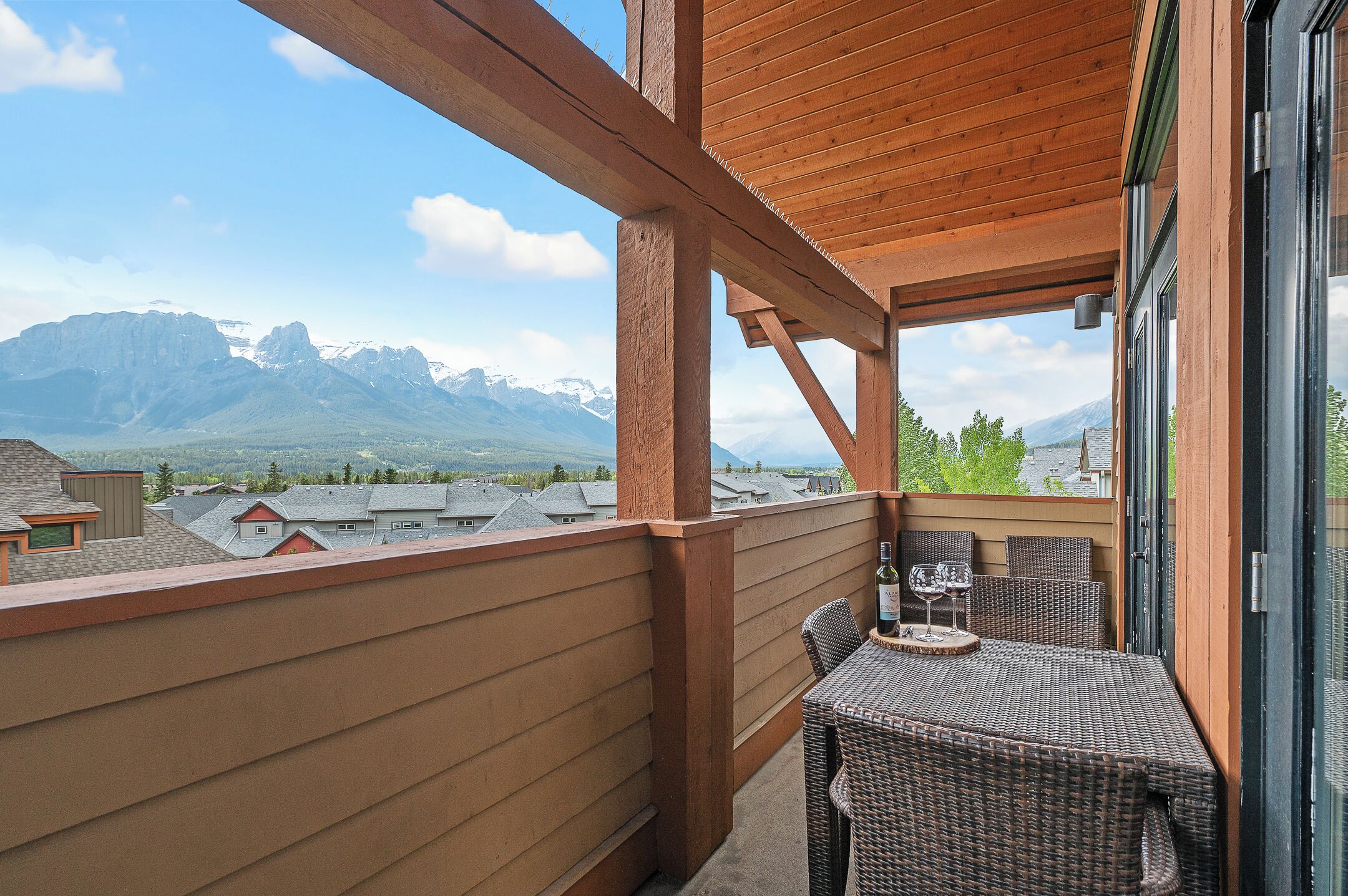 Ein Balkon mit Holzgeländer, Korbmöbeln und Blick auf Berge.