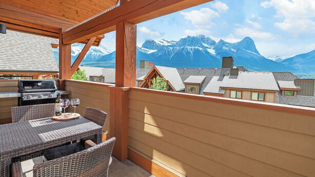 A balcony with a wooden ceiling and a view of snow-capped mountains. - Magnificent Mountain Penthouse - Pool & Hot Tub (Canmore)