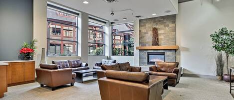 A spacious lobby with leather sofas, a fireplace, large windows, and a stone accent wall.
