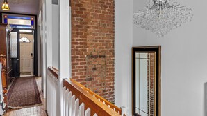 A wooden staircase with a white railing, a brick wall, and a chandelier. - Elegant Victoria 2BR 1.5BA & Private Yard (St. John's)