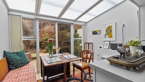 A conservatory with a dining area, a sofa, and a table with chairs. - Elegant Victoria 2BR 1.5BA & Private Yard (St. John's)