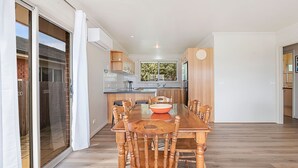 A spacious kitchen with a dining area, featuring a large table and chairs, a window with a view, and a sliding glass door leading to an outdoor area.