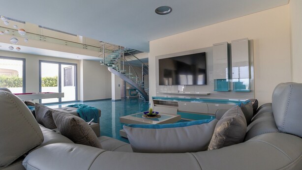 Una sala de estar moderna con piscina, una escalera y un televisor grande.
