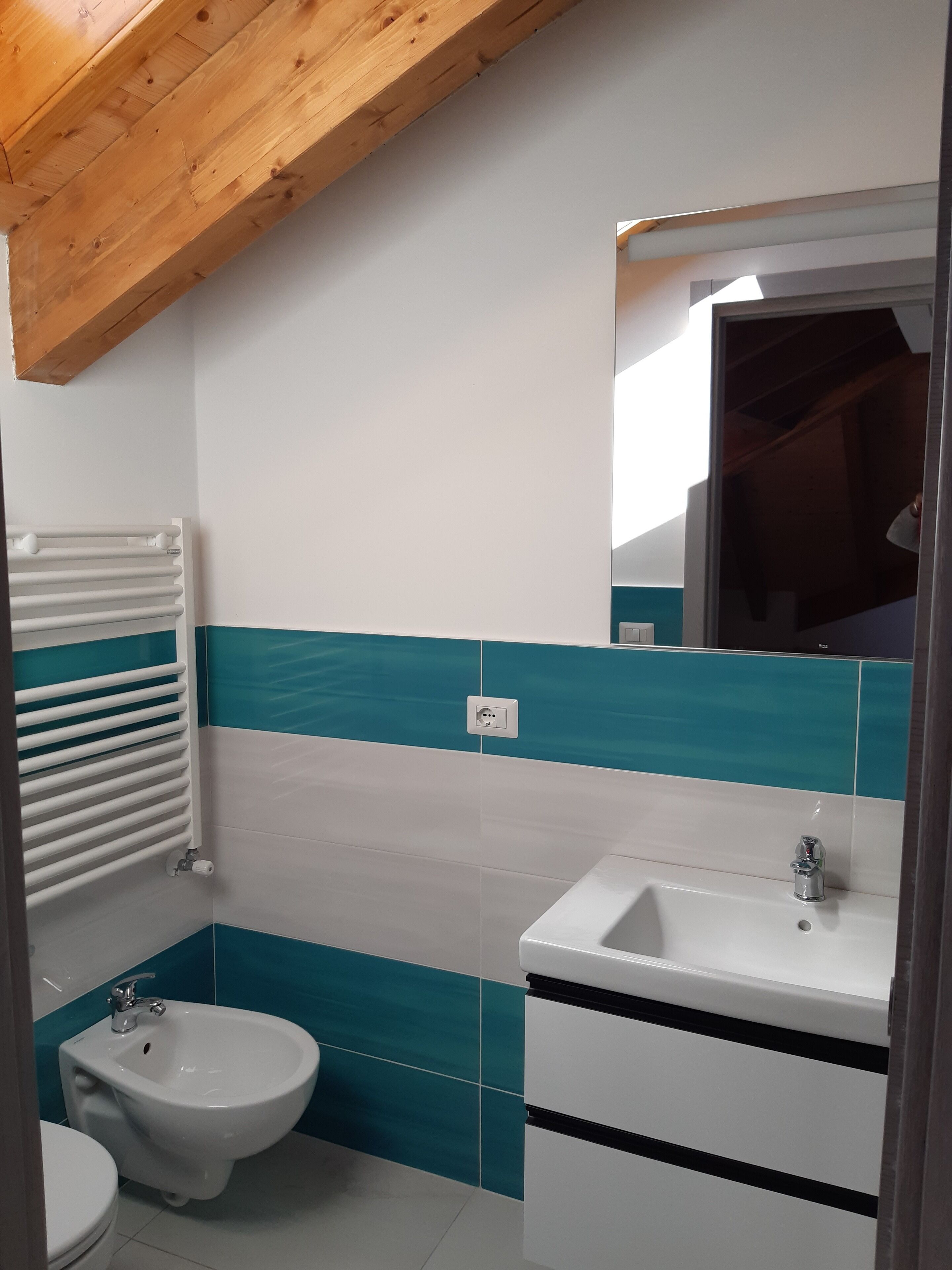A bathroom with a white sink, a bidet, and a towel rack.