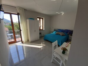 A bedroom with a bed, a desk with a chair, a wardrobe, and a balcony with a table and chairs. - Raggio di Sole (Pianillo)