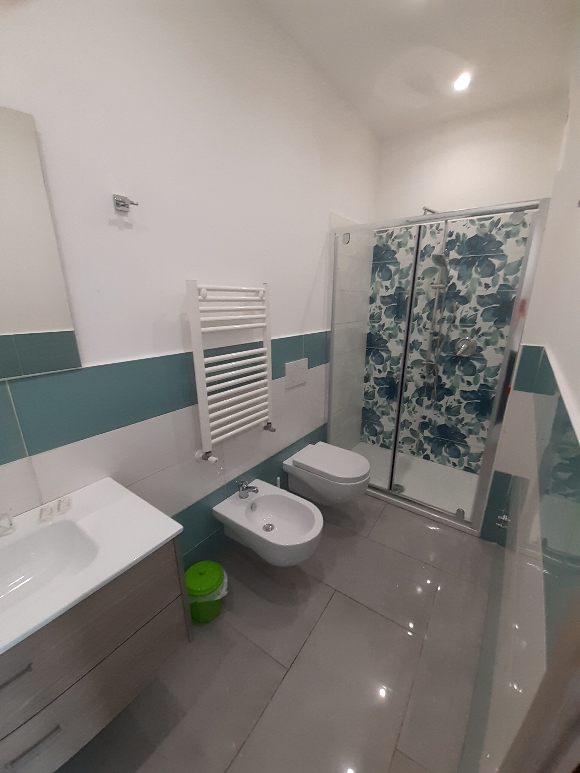 A bathroom with a sink, bidet, toilet, and shower.