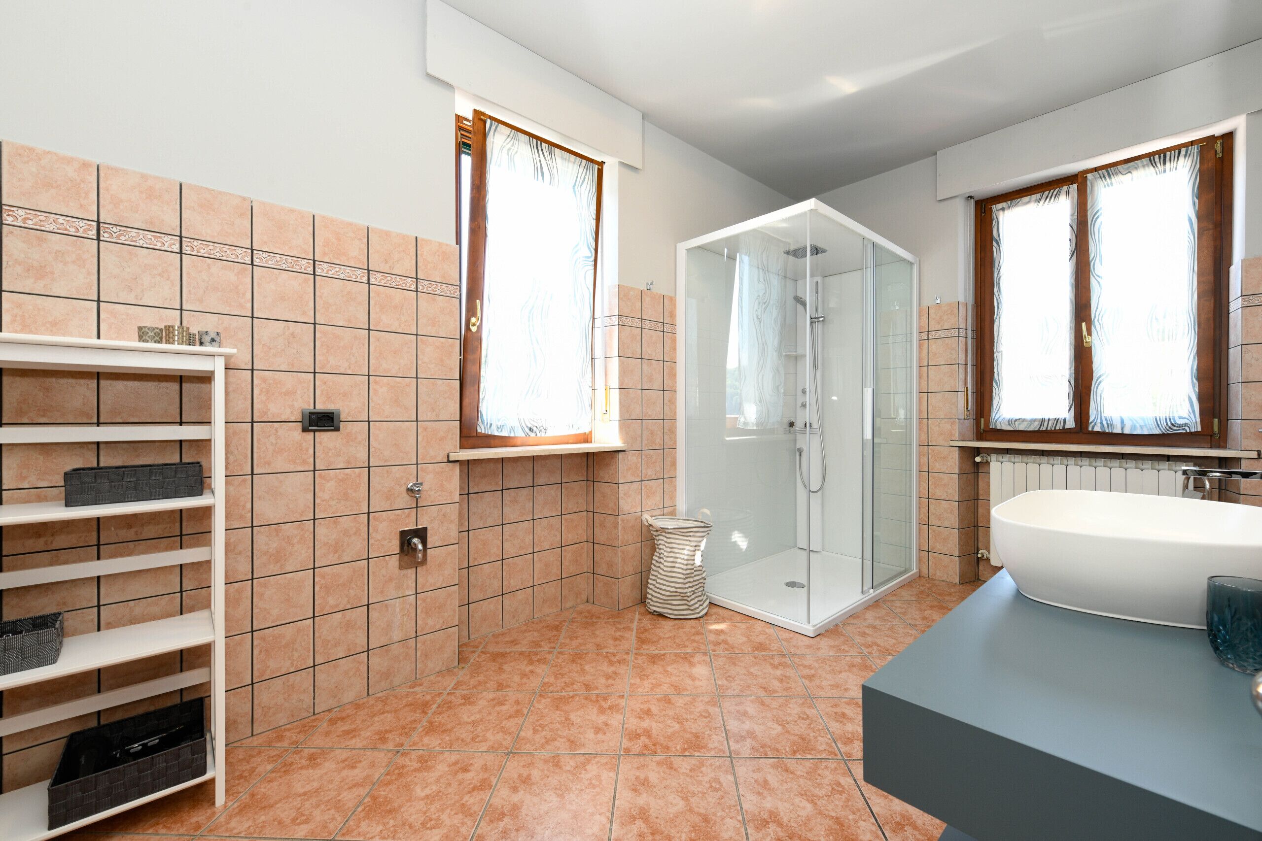 A modern bathroom with a glass-enclosed shower, a large bathtub, and a vanity with a mirror.