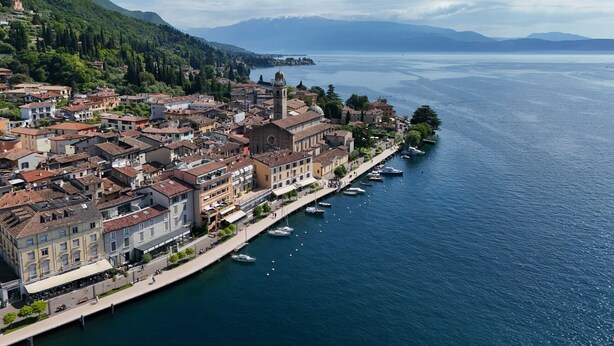 A coastal town with a prominent church, a marina, and buildings along the waterfront. - La Vela Deluxe lakefront in Salò (Salò)