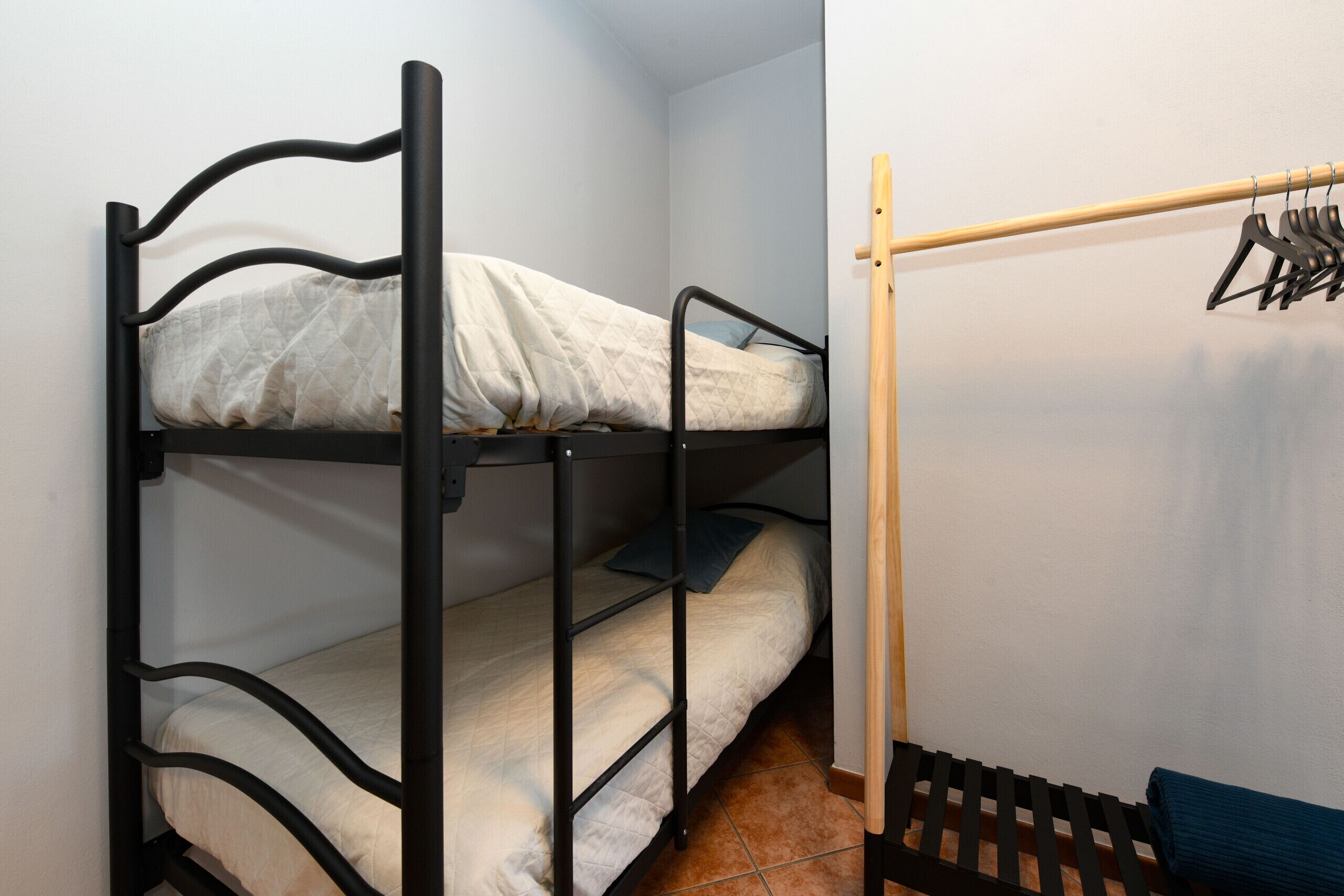 Ein Stockbett mit einer Holzleiter und einem Kleiderständer.