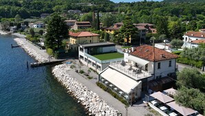 A coastal building with a terrace overlooking the sea, adjacent to a rocky shoreline. - La Vela Deluxe lakefront in Salò (Salò)