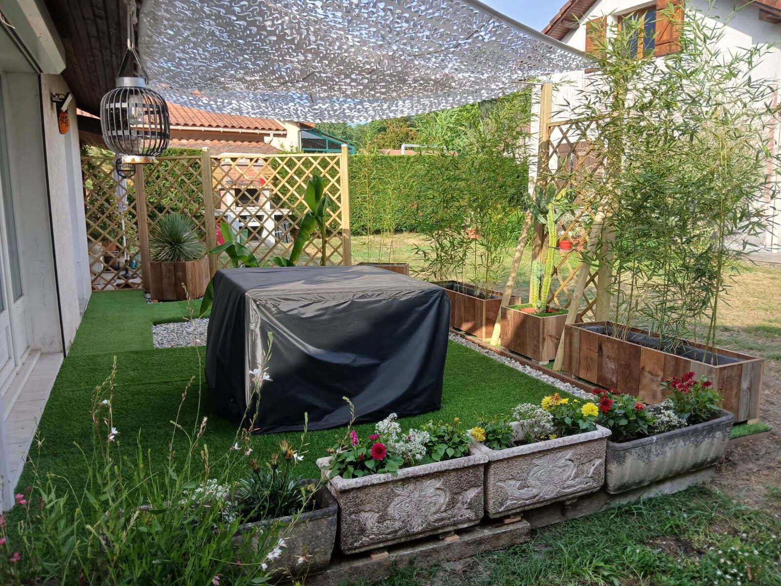 A garden with a covered table, a pergola, and various plants.