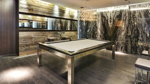 Una mesa de billar moderna en una habitación con paneles de madera y paredes de mármol.