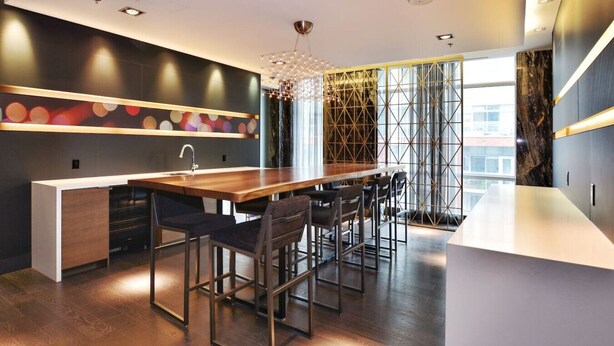 Una cocina moderna con una isla de madera, taburetes de bar y una lámpara decorativa.