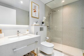 Een moderne badkamer met een grote spiegel, een witte wastafel en een douche met glazen wanden.