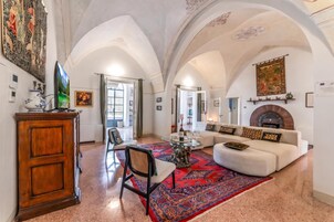 Amplia sala de estar con chimenea, un sofá, una mesa de centro y un tapete decorativo.