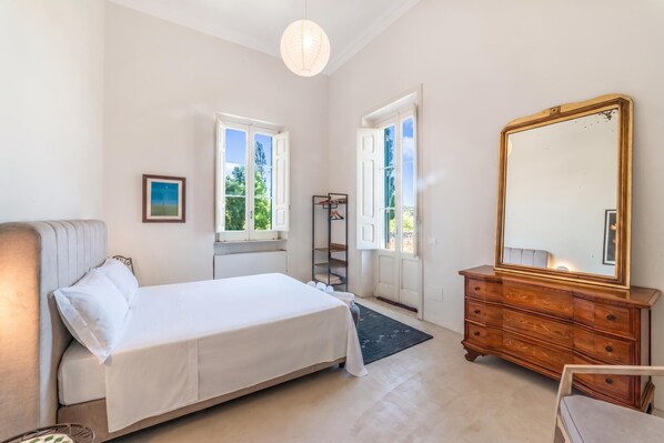 Une chambre à coucher avec un lit, une commode, un miroir et une fenêtre.
