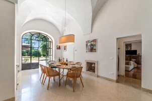 Un comedor con techo alto abovedado, un ventanal grande y una chimenea.